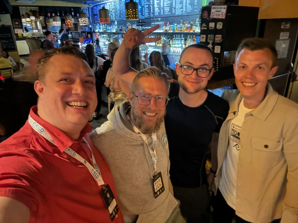 A selfie of four people smiling, stood in a bar.